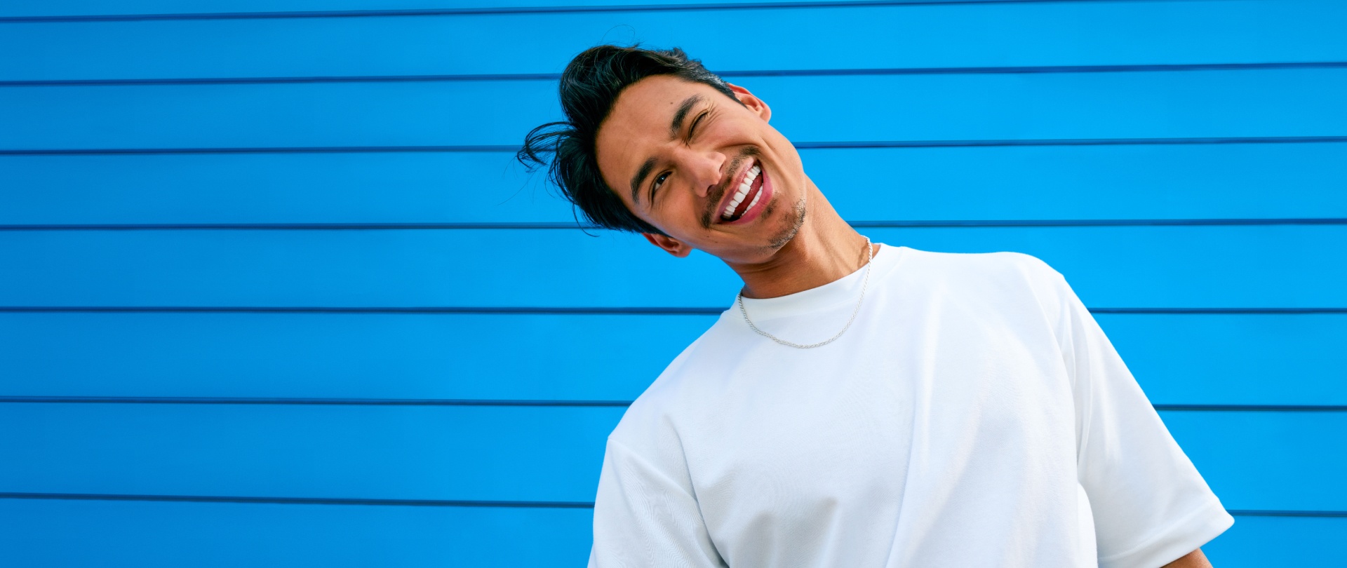 A winking-eye man wearing a white t-shirt on a blue background - ZYN