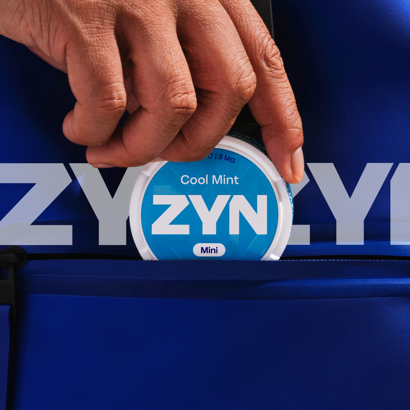 Hand putting a blue ZYN nicotine pouch can in a pocket