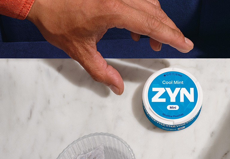 Hand grabbing a can of blue ZYN Cool Mint nicotine pouches
