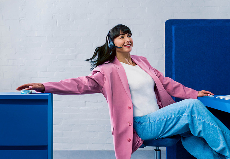 Woman wearing jeans and a pink jacket, listening to music and dancing