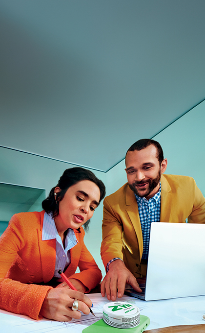 Man and woman talking in the office; a ZYN nicotine pouch can on the table
