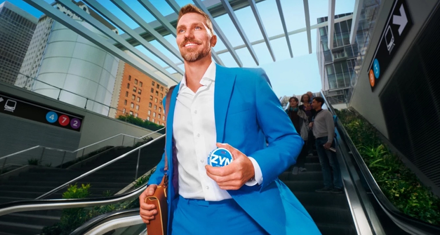 Person in blauem Anzug hält eine ZYN-Dose in der Hand und geht eine Rolltreppe hinunter.