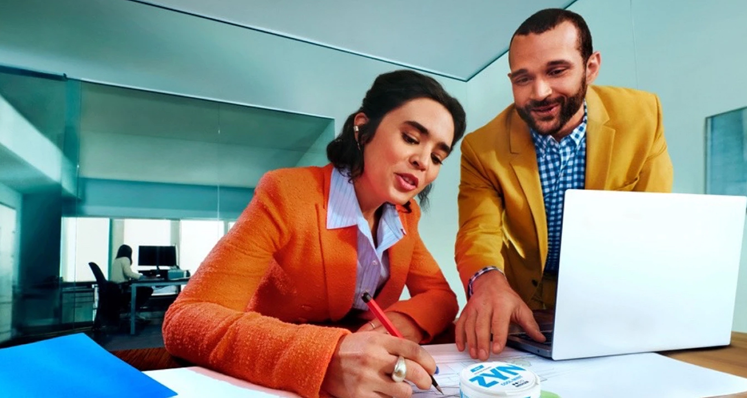 Zwei Personen arbeiten gemeinsam an einem Schreibtisch, ZYN-Dose liegt gut sichtbar auf den Unterlagen vor ihnen.