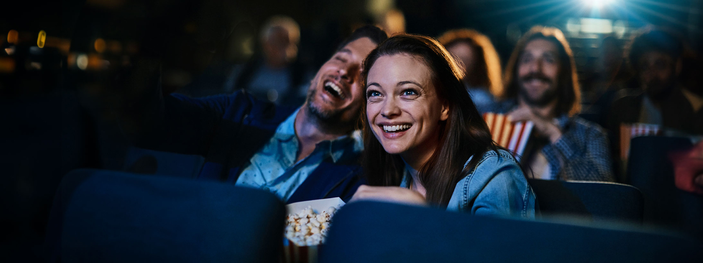 A man and a woman laughing at the cinema.