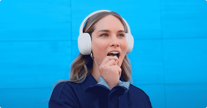Woman wearing a blue sweater, listening to music while trying a ZYN nicotine pouch