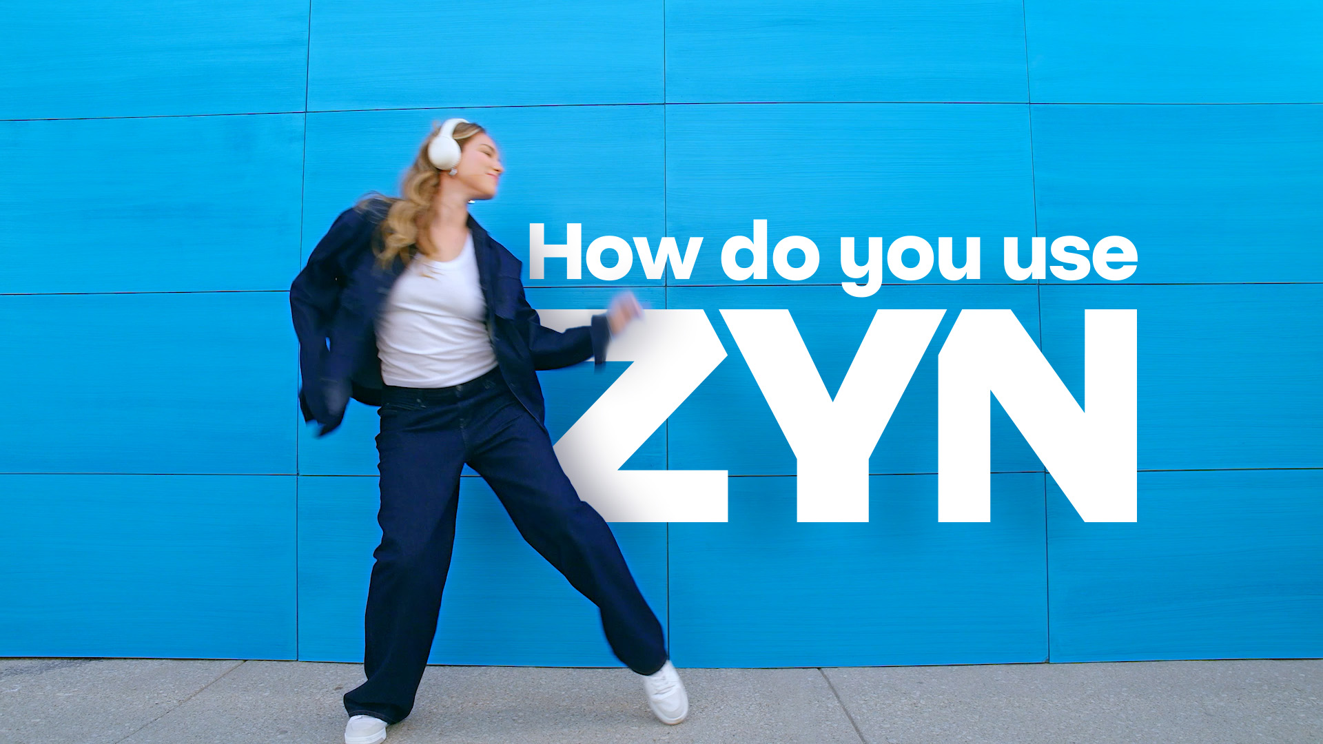 Woman wearing a blue sweater, listening to music while trying a ZYN nicotine pouch