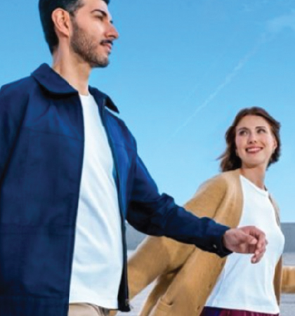 Image of a man and a woman walking with suitcases.
