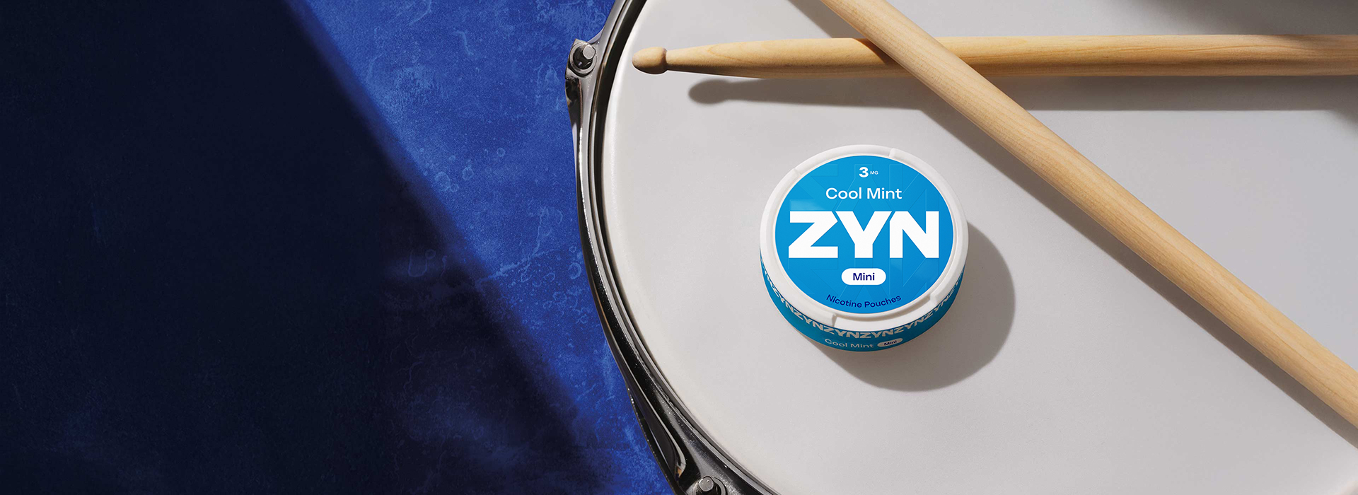Une boîte de sachets de nicotine ZYN Cool Mint bleue 3 mg Mini posée sur un intrument de musique