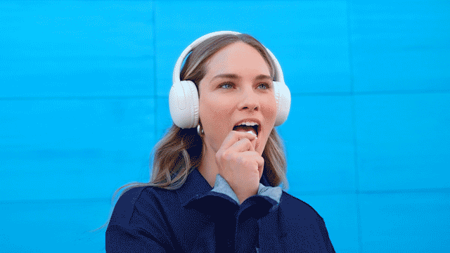 Mujer con suéter azul, escuchando música mientras prueba una bolsita de nicotina ZYN