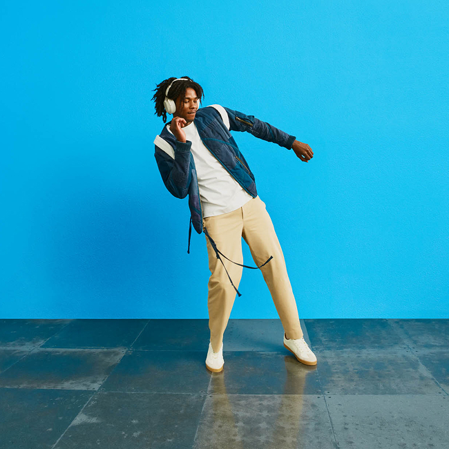 Hombre con auriculares y mochila escuchando música y bailando - logotipo azul de ZYN en el fondo