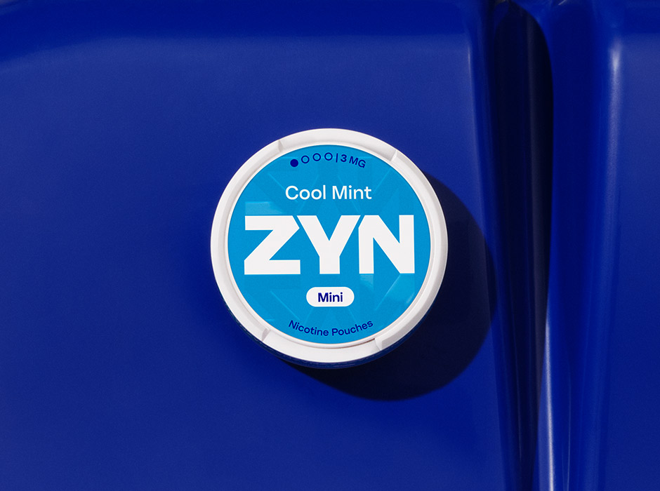 Niebieskie opakowanie saszetek nikotynowych ZYN Cool Mint leżące na granatowym plastikowym siedzisku